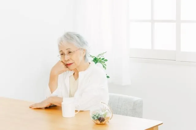 考え事をする白い服を着た60代女性